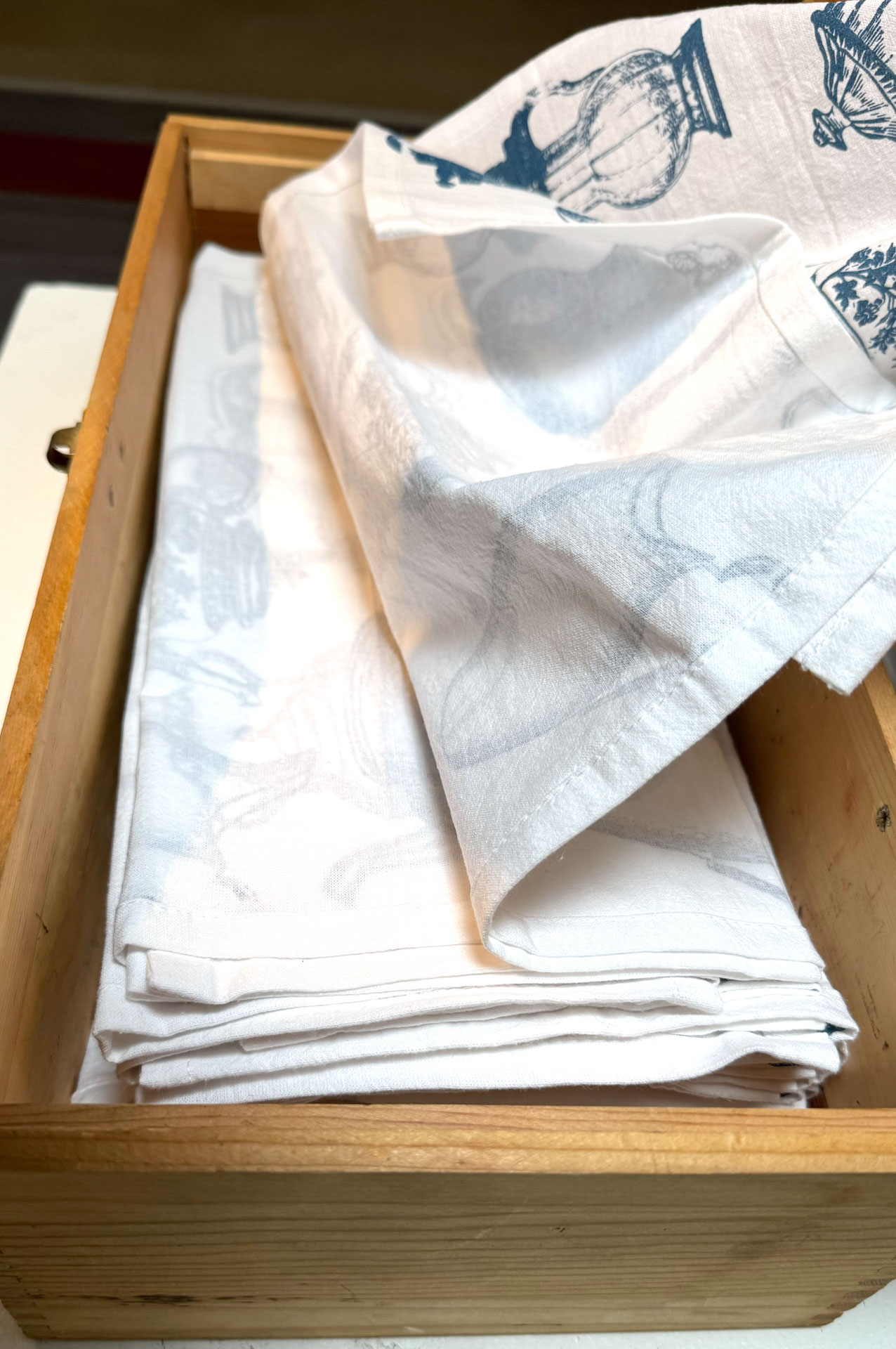 installation with installation with silkscreen napkins attached to ceiling in an arch travelling from a box to a pitcher