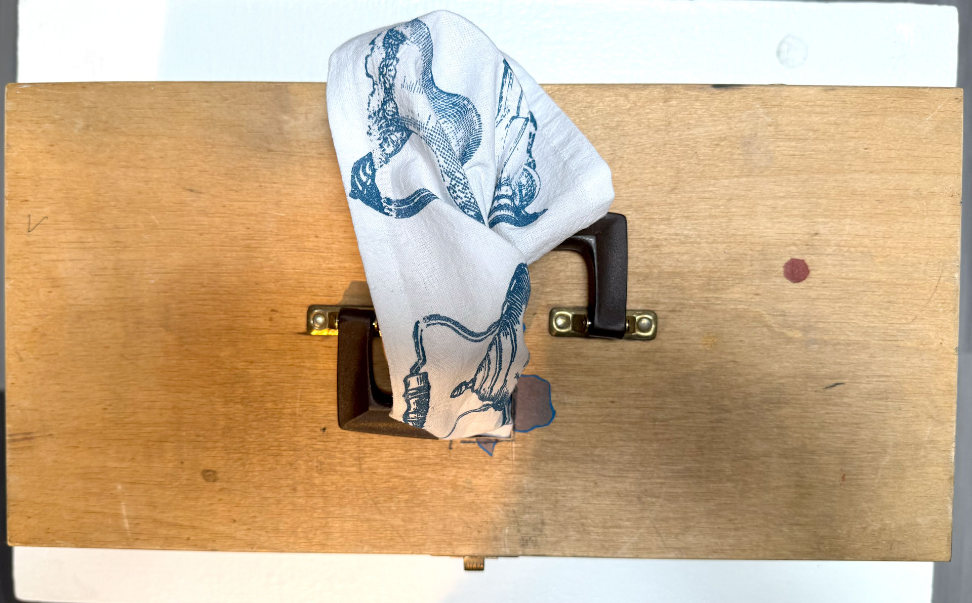 installation with installation with silkscreen napkins attached to ceiling in an arch travelling from a box to a pitcher