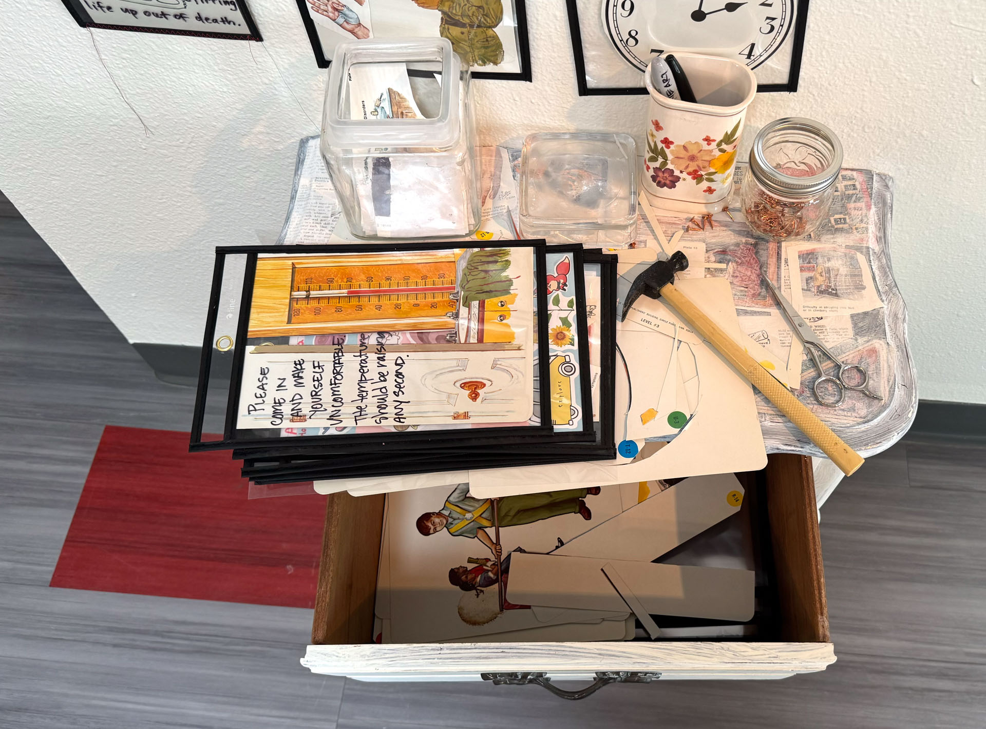installation with wood table cut in half against wall, job folder, collage materials, audience participation