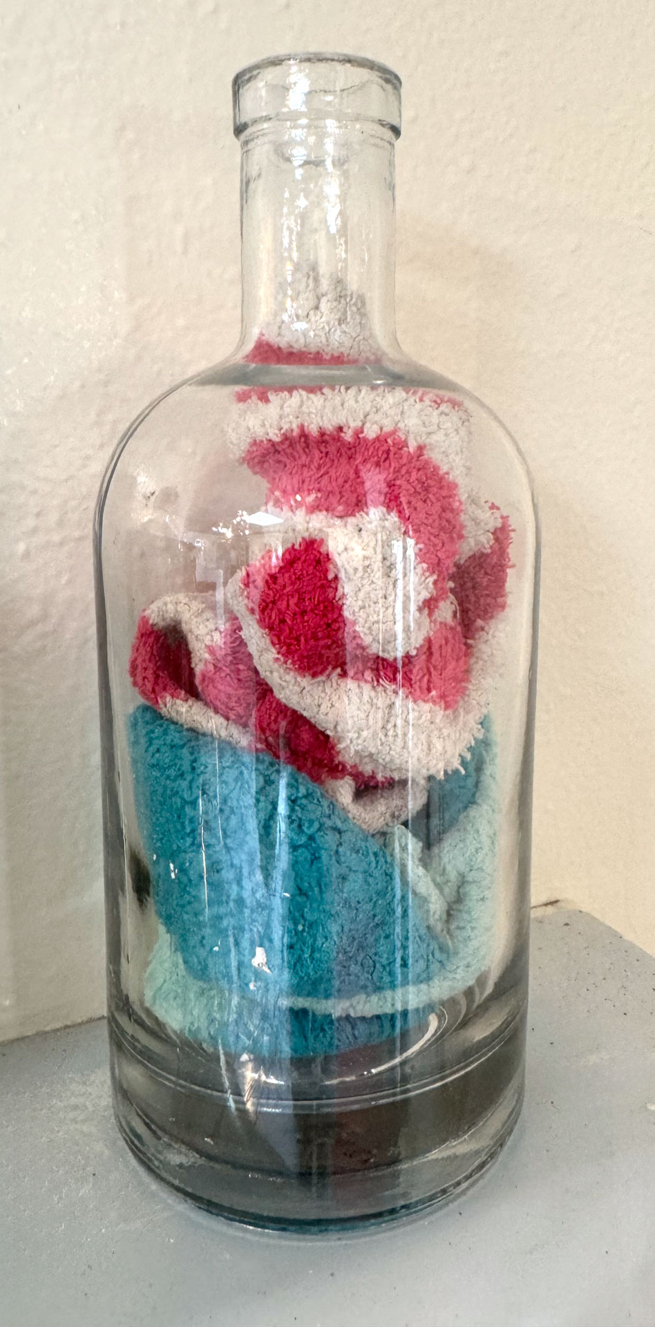 wall installation with glass jars containing harware, cutlery, yarn, fabric, collaged shelves