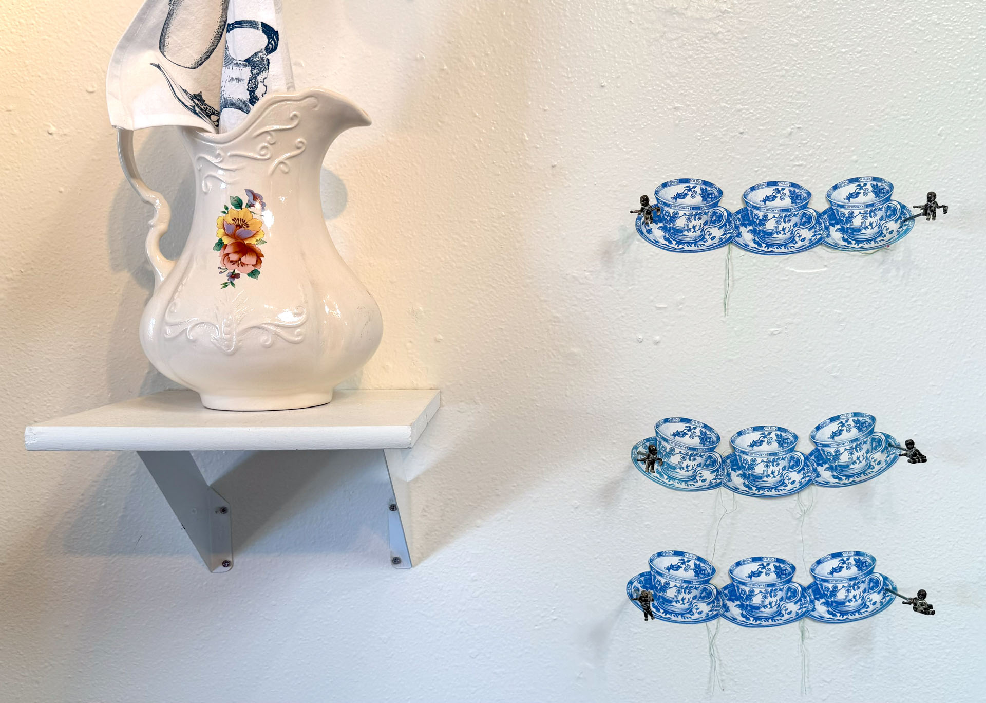 installation with installation with silkscreen napkins attached to ceiling in an arch travelling from a box to a pitcher