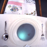 upholstered chair from video installation of stop-motion projected onto dinner plate from below at dinner table setting